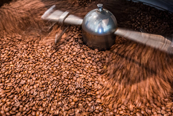 Roasted spinning cooler professional machines and fresh brown coffee beans movement close up dark photo at factory, motion blur effect. Closeup of fresh brown coffee seed roasting - Valokuva, kuva