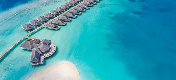 Letecký výhled na ostrov Maledivy, luxusní vodní vily a dřevěné molo. Krásné zázemí oceánu laguny pláž. Letní dovolená a koncept cestování. Vzdušná krajina ráje - Fotografie, Obrázek