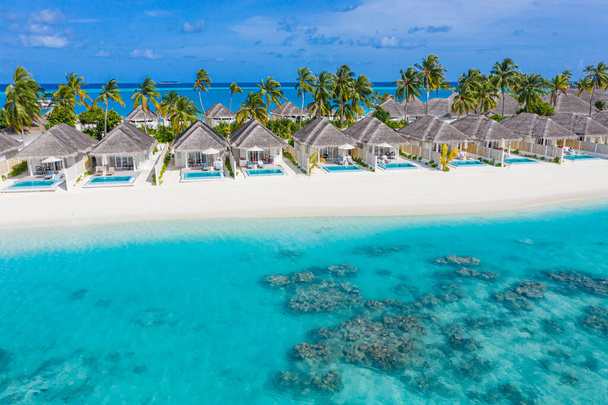 Photo aérienne de la belle plage tropicale paradisiaque des Maldives. Vue imprenable, lagon bleu turquoise, palmiers et plage de sable blanc. Destination de voyage de luxe. Paysage aérien ensoleillé - Photo, image