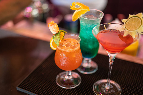 Tres coloridos cócteles gin tonic de frutas en vasos en el mostrador del bar en el pub o restaurante. Cócteles de colores brillantes - Foto, Imagen