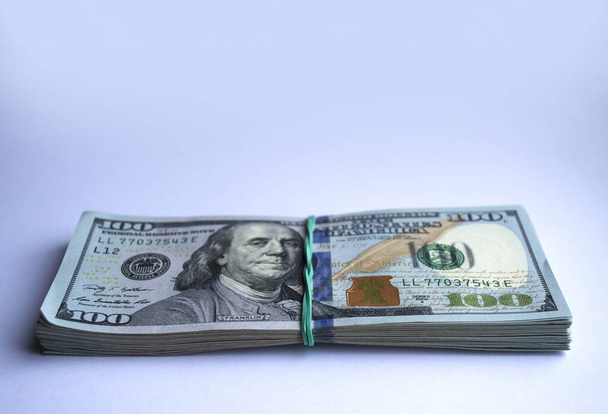 Billets en dollars rembobinés avec élastique sur fond blanc - Photo, image