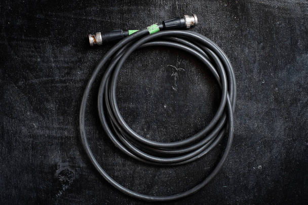 Schwarzes Kabel zur Übertragung des sdi-Signals durch bnc-Stecker auf dunklem Hintergrund - Foto, Bild