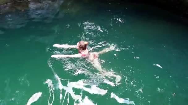 Ένα κορίτσι κολυμπάει σε ένα τυρκουάζ βαθύ ποτάμι που ρέει σε ένα φαράγγι ανάμεσα στα φαράγγια. - Πλάνα, βίντεο