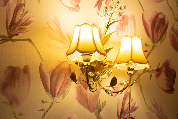 lámpara de araña montada en la pared incluida en la habitación en un estilo retro por la noche, iluminación eléctrica en el apartamento - Foto, Imagen