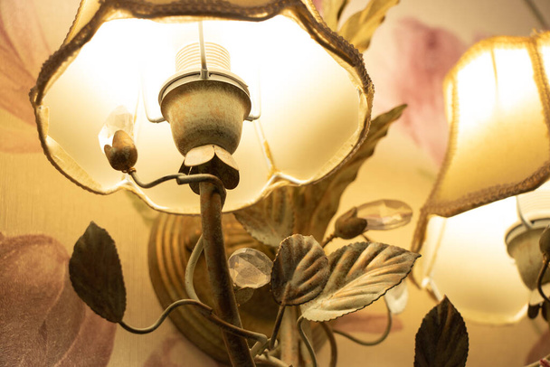 lámpara de araña montada en la pared incluida en la habitación en un estilo retro por la noche, iluminación eléctrica en el apartamento - Foto, imagen