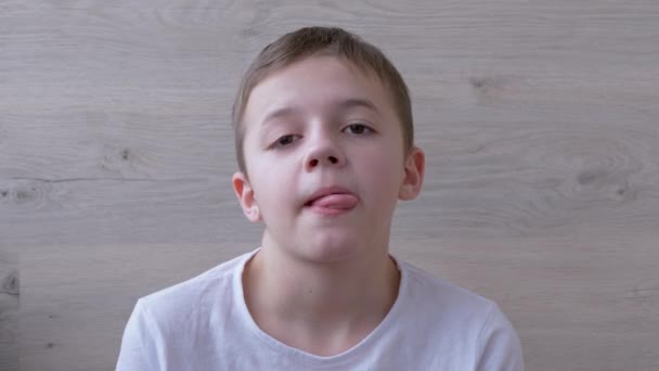 Chłopak z pełnymi ustami, długimi rzęsami robi Grimaces, wystaje z języka. Żarty. 4K - Materiał filmowy, wideo