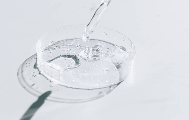 Gel líquido transparente o ácido sérico hialurónico en placa médica petri con pipeta. Concepto hidratante y cuidado de la piel - Foto, Imagen