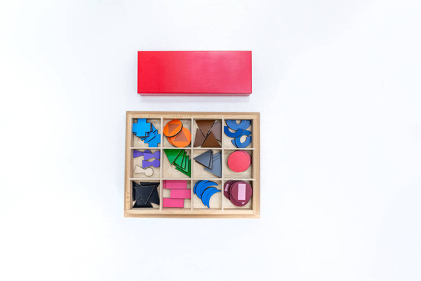 Horní pohled na dívky ruka hraje a třídění puzzle barevných dřevěných geometrických tvarů ve škole montessori. Koncepce využití vzdělávacích zdrojů pro výuku dětského jazyka a psaní. - Fotografie, Obrázek