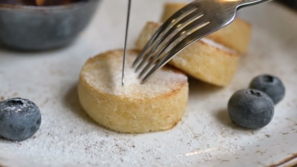 Kovová vidlička a nůž krájení sýrové palačinky kus v kavárně - Záběry, video