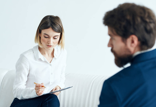 Egy nő dokumentumokkal hallgatja meg egy férfi problémáit egy könnyű hátterű pszichológussal. - Fotó, kép