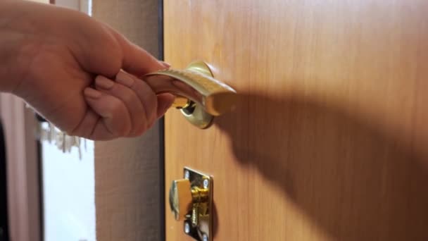 Γυναίκα κλείνει και κλειδώνει ξύλινη πόρτα χρυσό μεταλλικό πόμολο - Πλάνα, βίντεο