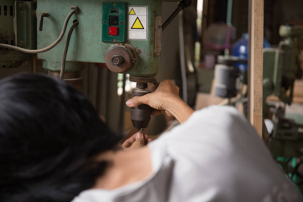 close up jovem trabalhador do sexo masculino usando uma máquina de broca na fábrica - Foto, Imagem