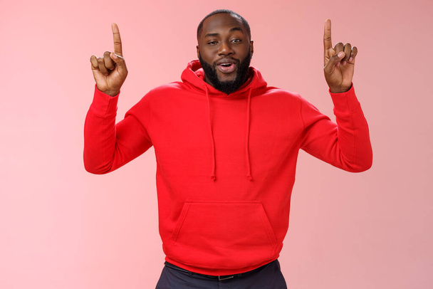Arroganter junger Mann prahlt gut aussehende freche afrikanisch-amerikanische bärtige Kerl zeigt erhobenen Zeigefinger nach oben grinsend selbstbewusst aussehen, empfiehlt erstaunliche Produkt, rosa Hintergrund - Foto, Bild