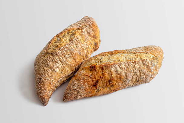 Dois pães de centeio e farinha de trigo, com cortes em cima de uma crosta dourada assada, com a adição de sementes de linho e sementes de gergelim - Foto, Imagem