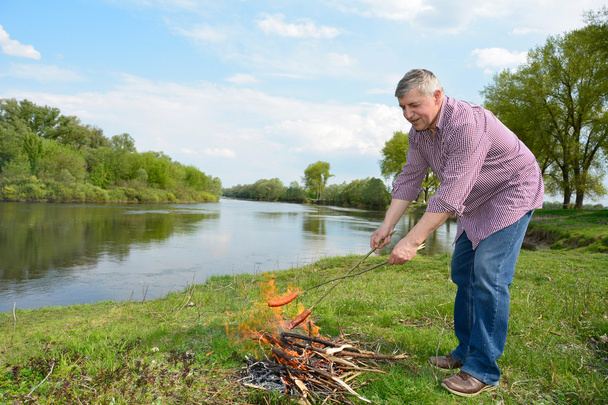 Homme en feu près de la rivière frites saucisses
. - Photo, image