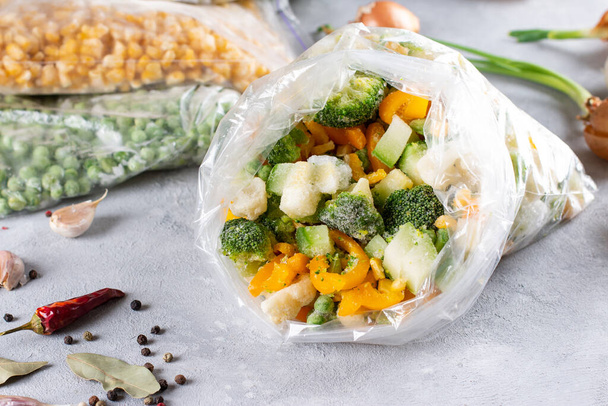 Verduras mixtas congeladas en una bolsa sobre un fondo de hormigón ligero. Comida congelada. Almacenamiento de alimentos - Foto, Imagen