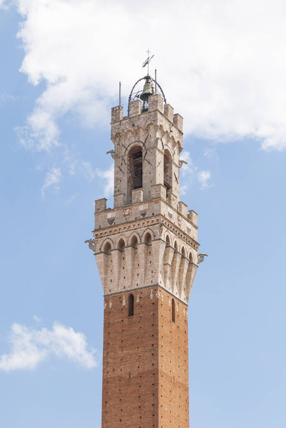 Вид на средневековую башню Torre del Mangia, расположенную на площади Пьяцца дель Кампо, это одна из самых знаковых достопримечательностей Сиены, Италия - Фото, изображение