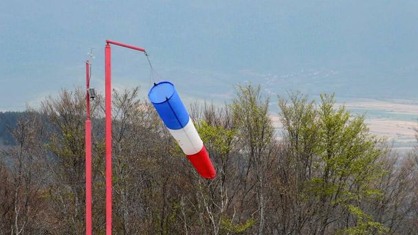 chaussette de vent - pointeur rouge, bleu et blanc indiquant la force et la direction du vent contre le ciel bleu - Photo, image