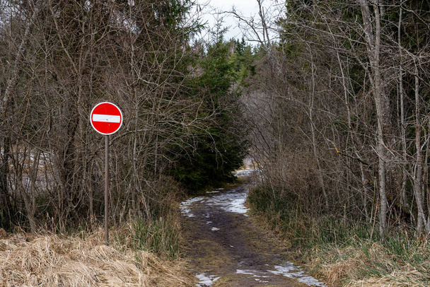 El camino en el campo letón que entra en el bosque y hay una señal de no ir está prohibido. - Foto, Imagen