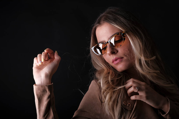 Italian girl with long blond hair posing with leather jacket and sunglasses. High quality photo - Foto, Imagem