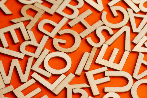 vista dall'alto dettaglio primo piano macro di molti taglio di legno lettere piccolo alfabeto su sfondo arancione - Foto, immagini