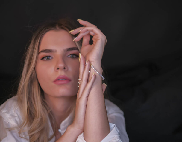 portrait of beautiful Italian girl with long blond hair with closed eyes bracelet and long nails. High quality photo - Zdjęcie, obraz