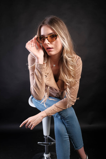 Italian girl with long blond hair posing with leather jacket and sunglasses. High quality photo - Фото, изображение