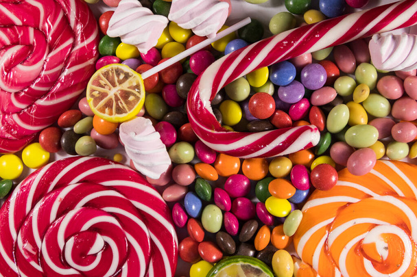 Tło kolorowych cukierków czekoladowych, lizaków, trzciny cukrowej i pianek - Zdjęcie, obraz