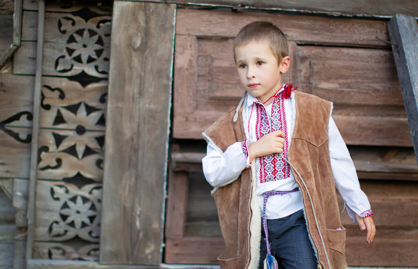 Μικρό αγόρι με σλαβικά εθνικά ρούχα σε ξύλινο φόντο. Λευκορώσο ή Ουκρανό παιδί με κεντημένο πουκάμισο. - Φωτογραφία, εικόνα