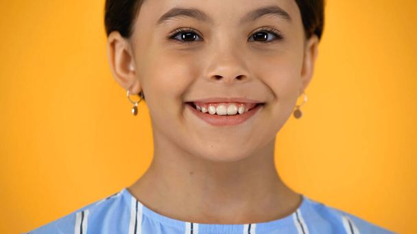 close-up van gelukkig kind op zoek naar camera geïsoleerd op geel - Foto, afbeelding