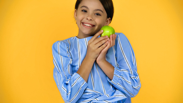 黄色に隔離された緑のリンゴを持っている陽気な子供 - 写真・画像
