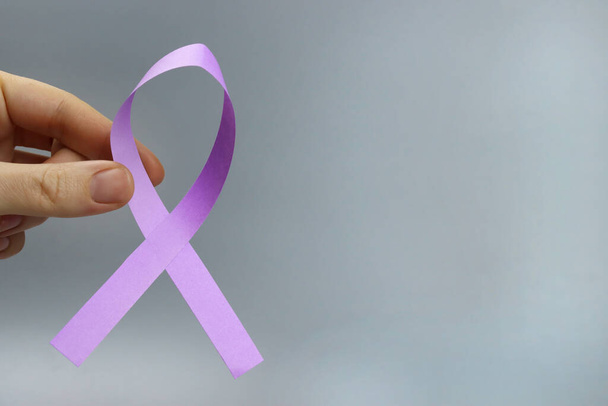 фиолетовая лента в руке, символ эпилепсии, болезнь Альцгеймера, рак поджелудочной железы, рак щитовидной железы - Фото, изображение