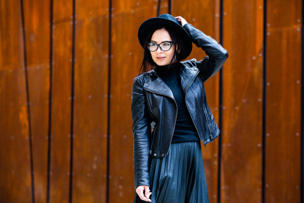 Menina russa bonita vestida com roupas de couro preto e óculos. Estilo rock mulher europeia em fundo urbano. - Foto, Imagem