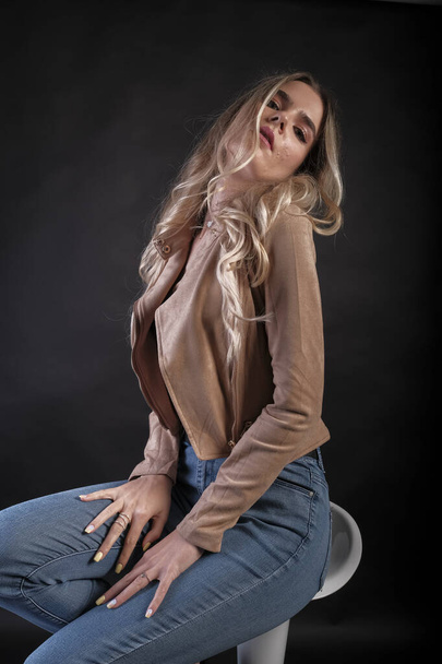 Italian girl with long blond hair posing with leather jacket. High quality photo - Фото, зображення