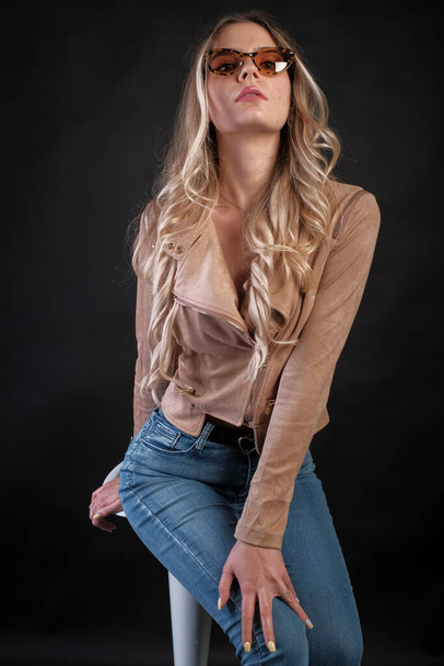 Italian girl with long blond hair posing with leather jacket and sunglasses. High quality photo - Foto, immagini