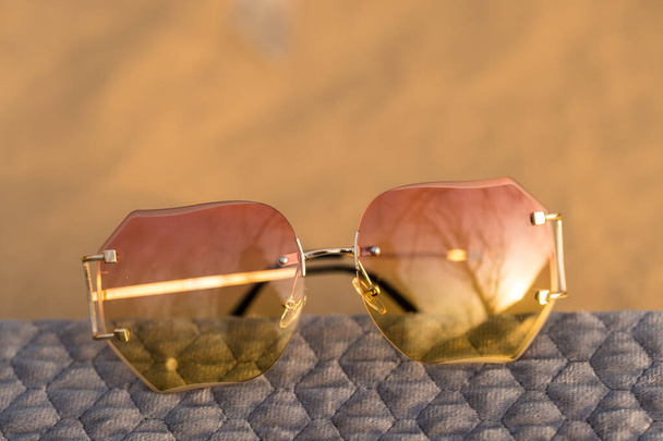 Futurystyczne okulary przeciwsłoneczne bezkresny design z różowymi soczewkami i złotą ramą strzelać na zewnątrz w słoneczny dzień. Skupienie selektywne  - Zdjęcie, obraz