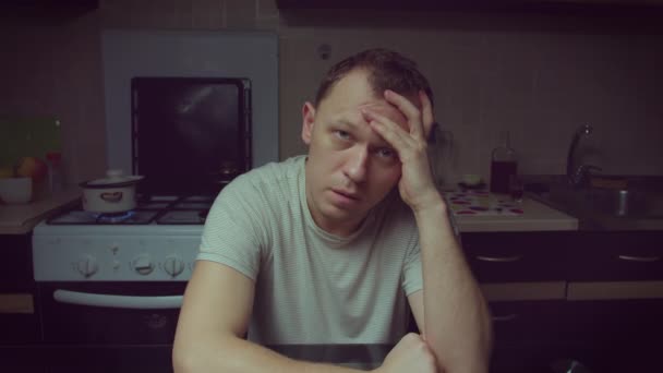 Portret van een jonge man die 's avonds aan de keukentafel zit, depressie, camerabeweging - Video