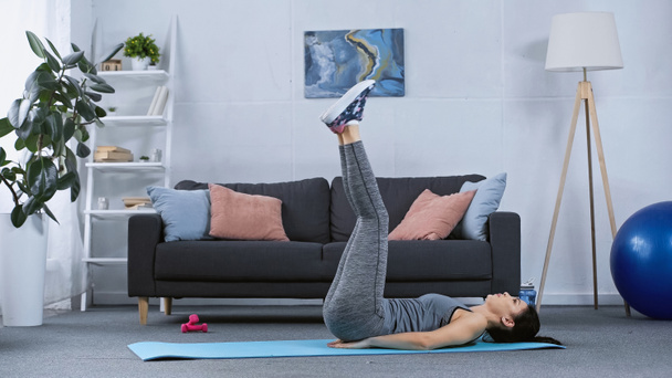 женщина в спортивной одежде работает на фитнес-коврик дома  - Фото, изображение