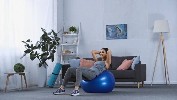 happy young woman in sportswear working out on fitness ball at home  - Photo, Image