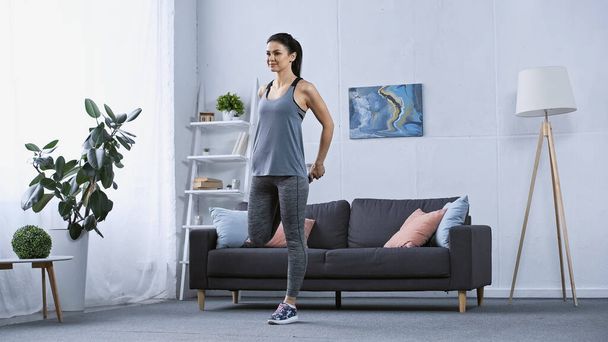 young woman in sportswear stretching at home  - Photo, Image