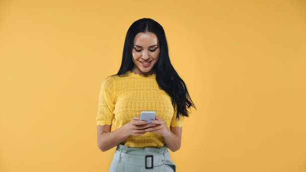 veselá žena zprávy na mobilním telefonu izolované na žluté - Fotografie, Obrázek