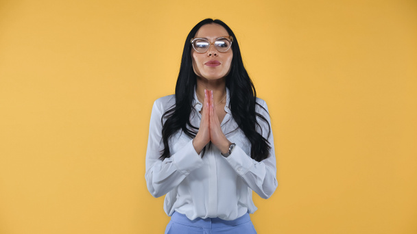 positive businesswoman with praying hands looking away isolated on yellow - Photo, Image