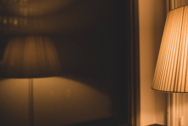 напольная лампа с теплым светом и отражением в окне - Фото, изображение