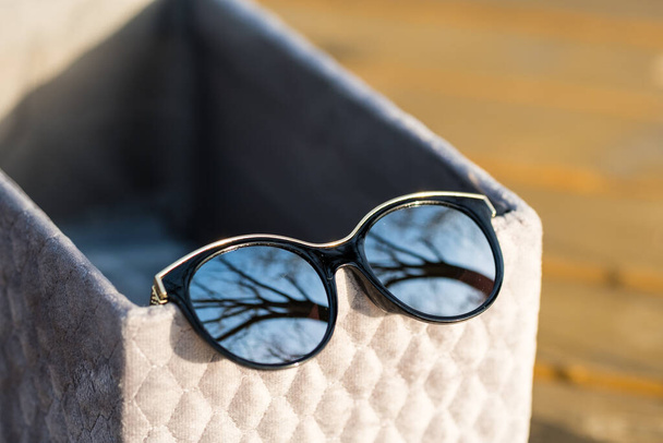 Fashion kattenoog zonnebril model voor dames met grote ronde zilveren lenzen en zwarte frame shoot buiten in een zonnige dag close-up. Selectieve focus  - Foto, afbeelding