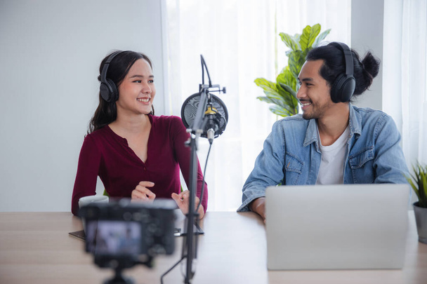 2つのアジアのラジオホストは、放送スタジオでポッドキャストを記録します,自宅で男とオンラインマイクで話してアジアの女性 - 写真・画像