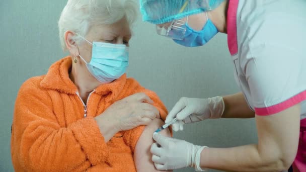 Operatore medico di laboratorio che effettua un'iniezione di vaccino anti-coronavirico con siringa e ago per pazienti anziani appartenenti a un gruppo di rischio in clinica - Filmati, video