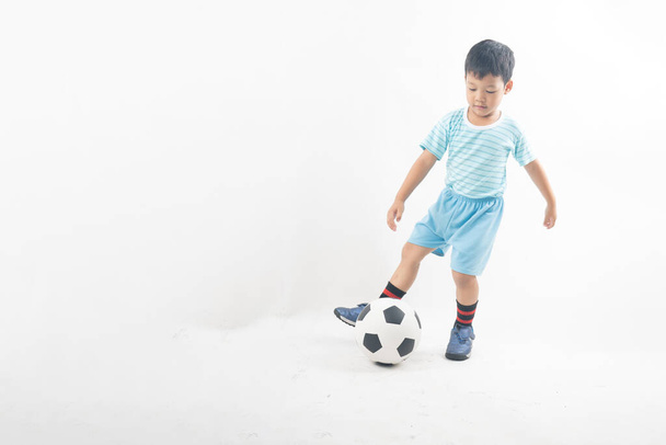 Νεαρό ασιατικό αγόρι κλωτσήσει ποδόσφαιρο απομονώνονται σε λευκό φόντο  - Φωτογραφία, εικόνα