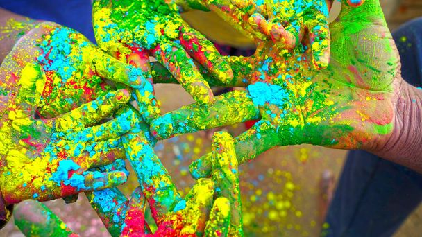 Multi hand met verschillende kleuren. Gesneden weergave van de hand met multi gekleurde Holi poeder. Heldere kleuren van Holi in de palm, close-up. - Foto, afbeelding