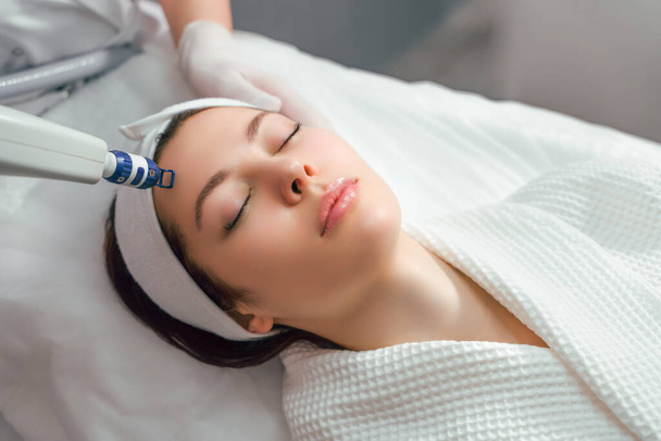 Una donna riceve il trattamento laser del viso in una clinica di cosmetologia, un concetto di ringiovanimento della pelle è in fase di sviluppo. peeling laser - Foto, immagini