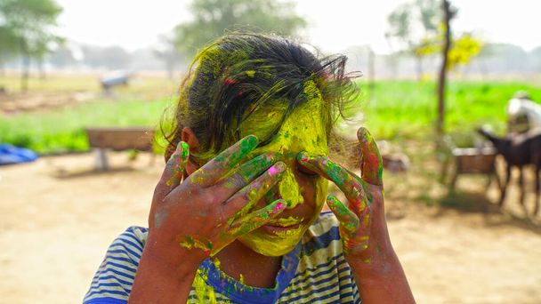 Szczęśliwego holi. Młoda wesoła dziewczyna pod wybuchem kolorowego proszku w kolorach Holi z makijażu. - Zdjęcie, obraz